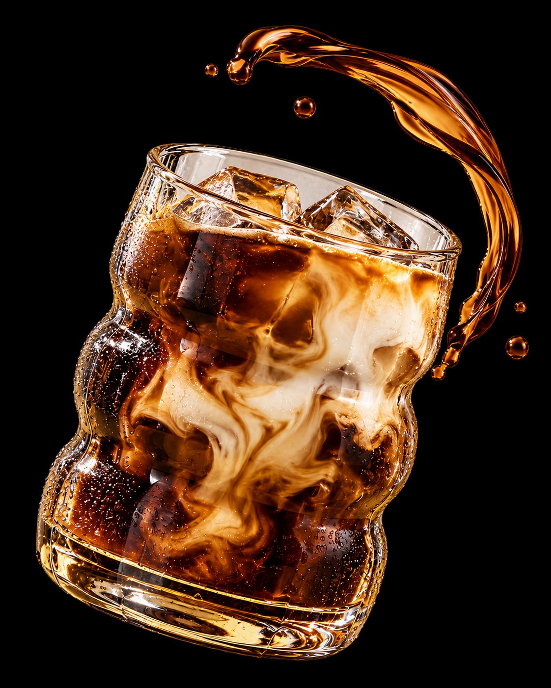 Vaso de café helado con crema, hielo y café suspendido sobre un fondo oscuro.